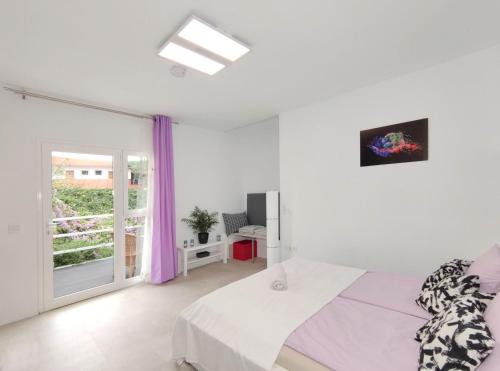 a white bedroom with a bed and a window at Fantastico 3 Puerto de la Cruz Tenerife, Free Parking, Air Conditioning, Netflix in Puerto de la Cruz