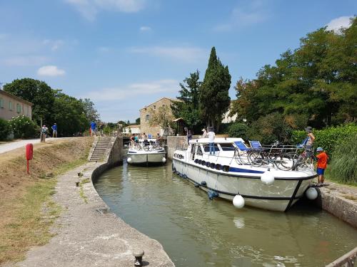 two boats are docked in a small canal at Le Bariole, luxury villa with heated pool in Cesseras