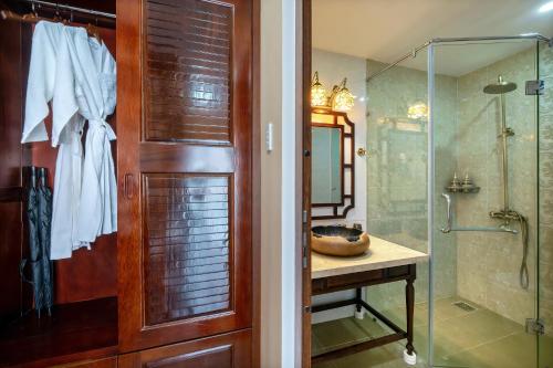 a bathroom with a shower and a wooden door at Hoi An May Village in Hoi An
