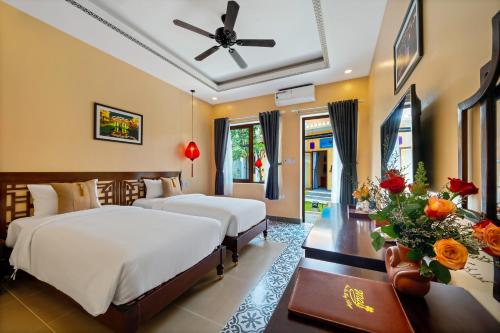 a bedroom with two beds and a ceiling fan at Hoi An May Village in Hoi An