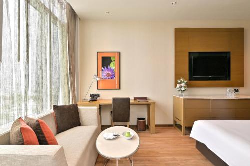 a living room filled with furniture and a tv at Eastin Grand Hotel Sathorn - SHA Extra Plus in Bangkok