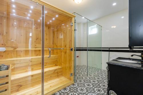 een badkamer met een douche en een houten muur bij Pallas Villa in Vung Tau