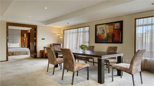 a dining room with a table and chairs and a bedroom at Marco Polo Parkside, Beijing in Beijing