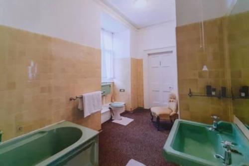 a bathroom with a green tub and a toilet at Home of author of the famous Jungle Book in Torquay