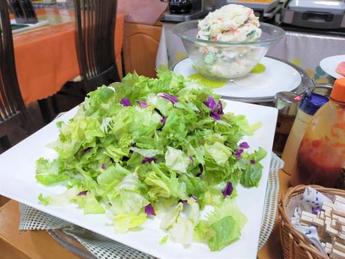 a plate of lettuce on a table with a bowl of salad at Tabist Business Hotel Takizawa Takasaki Station Nishiguchi in Takasaki