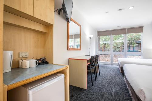 a room with a kitchen and a bed and a desk at Burvale Hotel in Nunawading