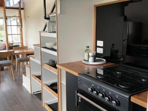 a kitchen with a black stove and a table at The Tiny Nest in Palmerston North