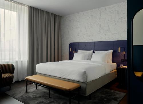 una camera d'albergo con un grande letto e una panca di Solo Sokos Hotel Helsinki a Helsinki