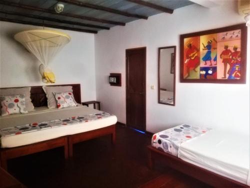 a bedroom with two beds and a painting on the wall at Hotel Les Boucaniers in Ambatoloaka