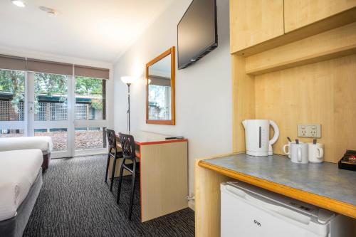 a hotel room with a bed and a kitchen with a counter at Burvale Hotel in Nunawading