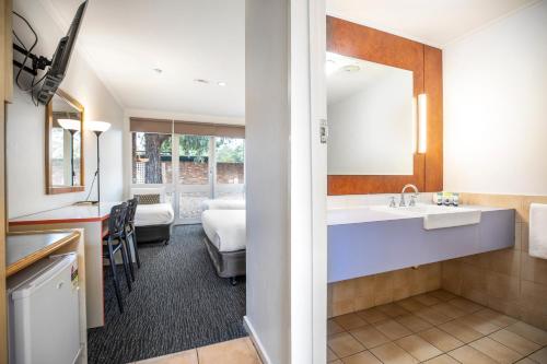 a bathroom with a sink and a room with a bed at Burvale Hotel in Nunawading