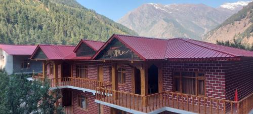 a building with red roofs with mountains in the background at Hotel Royal Hillcrest in Harsil