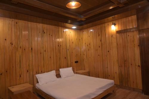 a room with a bed in a wooden wall at Hotel Royal Hillcrest in Harsil