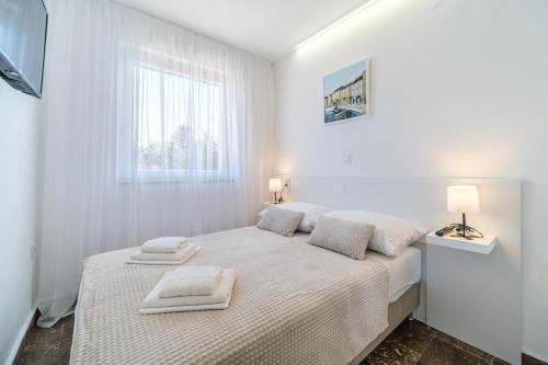a white bedroom with a bed with towels on it at ATJ house in Supetar