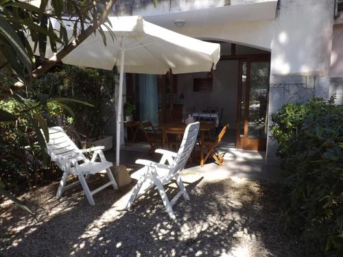 Un grupo de sillas y una sombrilla en un patio. en il faretto casale grandangolo, en Capoliveri