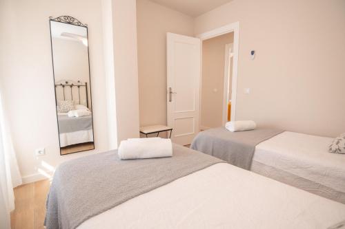 een witte kamer met 2 bedden en een spiegel bij Apartamento Plaza Mar in La Herradura