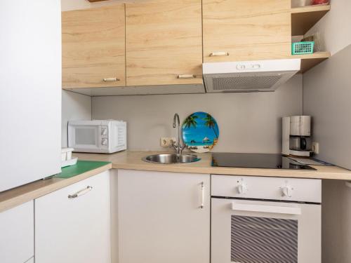 a kitchen with white cabinets and a sink at Apartment in Carinthia on Lake Woerthersee in Techelsberg am Worthersee