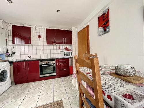 リクヴィールにあるAppartement 2 chambres au cœur du vignoble avec terrasseのキッチン(赤いキャビネット、テーブル、テーブルシドックスシドックス付)