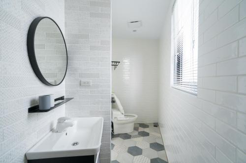 a white bathroom with a sink and a mirror at The Way Inn in Taichung