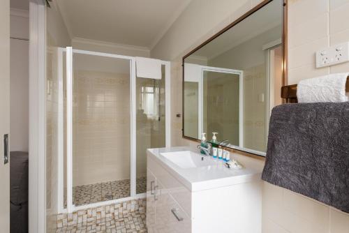 a bathroom with a sink and a shower with a mirror at Sunshine Coast Airport Motel in Marcoola