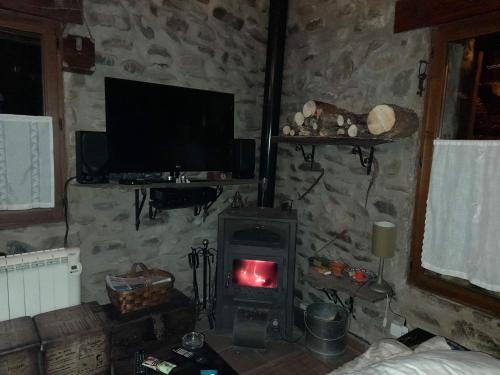 a living room with a wood stove with a tv at Zaldierna al sol, aldea del siglo XVIII Ezcaray in Zaldierna