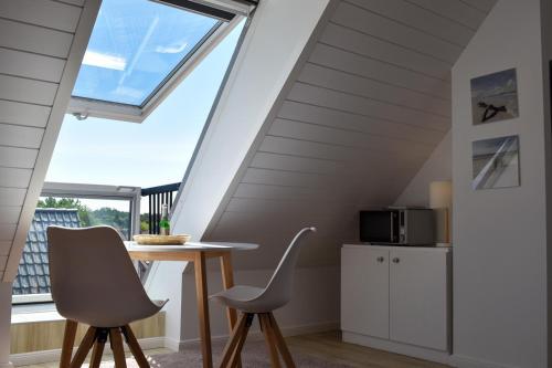 ein Esszimmer mit einem Tisch, Stühlen und einem Fenster in der Unterkunft Wohnung Wattwurm in Norderney