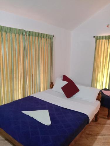 a bedroom with a bed with a blue and white blanket at Shivalaya Homestay, Madikeri in Siddapur