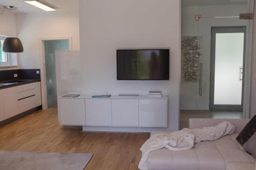 ein Wohnzimmer mit einem Sofa und einem TV an der Wand in der Unterkunft Haus Karlsbad - neu und modern in Velden am Wörthersee