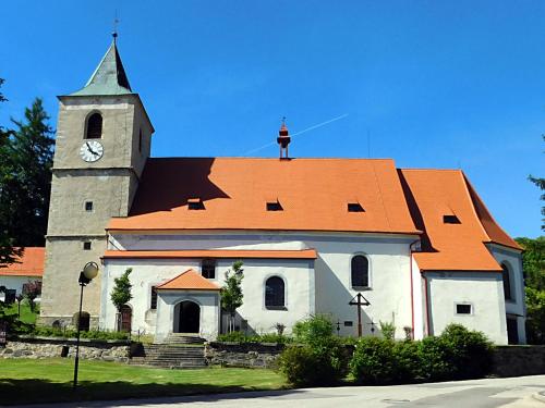 a church with an orange roof with a clock tower at Apartmány Horní Planá in Horní Planá