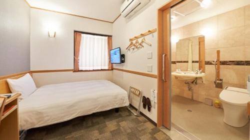 a bedroom with a bed and a bathroom with a sink at Toyoko Inn Nagoya Nishiki in Nagoya