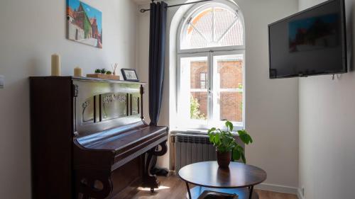 a room with a piano and a table and a window at Main Square Apartments in Toruń