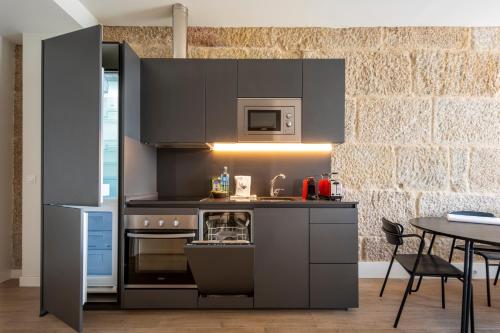 een keuken met zwarte kasten en een tafel met stoelen bij Bow Homes by Como en Casa in Vigo