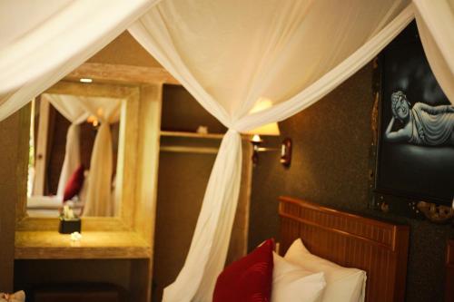 a bedroom with a bed with a canopy and a mirror at Kubuku Eco Dive Lodge and Yoga in Pemuteran