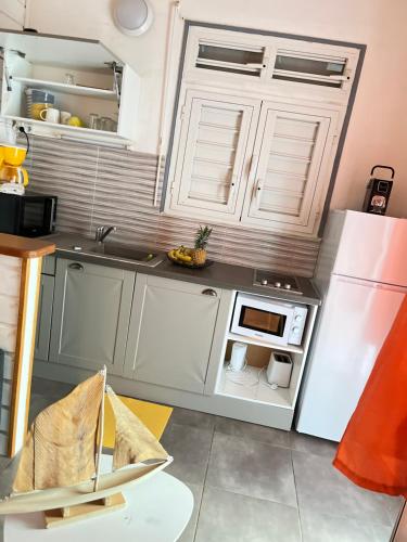 a kitchen with white cabinets and a refrigerator at Les algues de La Chapelle Bleu horizon in Anse-Bertrand