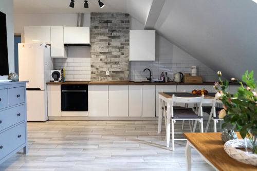a kitchen with white cabinets and a table in it at Apartament Przy Podziemiach in Chełm