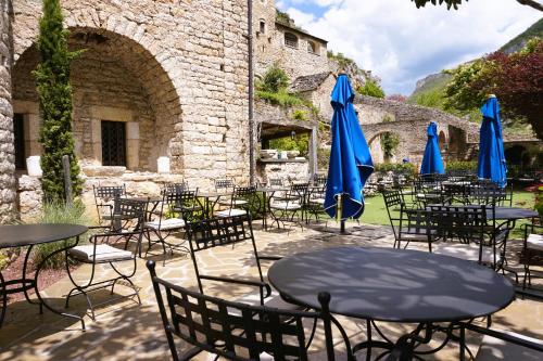 a group of tables and chairs with blue umbrellas at Hôtel-Restaurant Le Manoir De Montesquiou in La Malène
