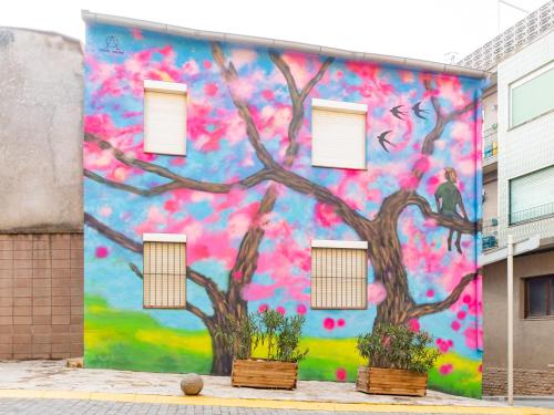 un mural de un árbol al lado de un edificio en Casa de l'Arbre, en Aitona