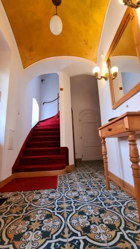 a room with a staircase with a red carpeted floor and a piano at Penzion Valkoun-Lilienfeld in Karlovy Vary