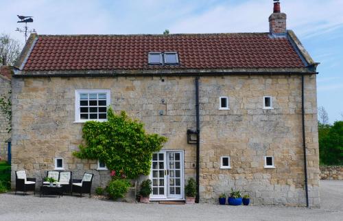 an old stone building with chairs in front of it at Crow House Barn in Copgrove