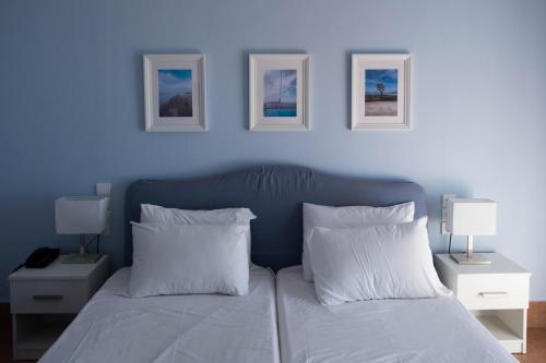 Mirtia Hotel في بيفكي: غرفة نوم زرقاء مع سرير مع وسائد بيضاء