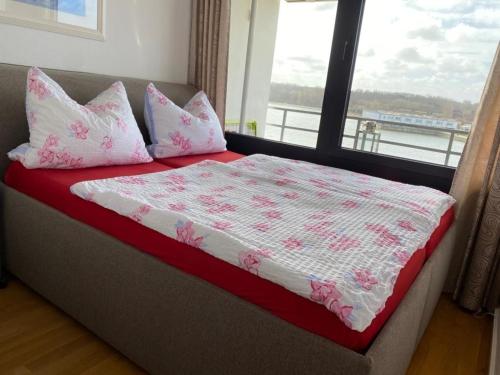 ハイリゲンハーフェンにあるArenz, Steinwarder 35 - 5 -19のピンクと白の枕が備わるベッド、窓が付いています。