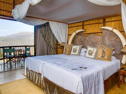 a bedroom with a large bed and a balcony at Mkuze Falls Private Game Reserve in Mkuze