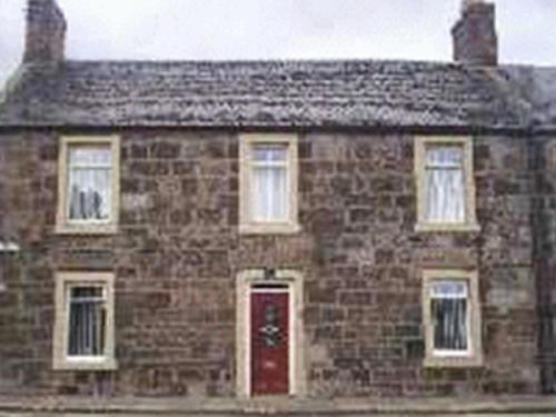 カーコーディにあるAshgrove Bed and Breakfastの赤い扉のある古いレンガ造りの家