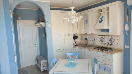 uma cozinha com armários brancos, uma mesa e um lustre em APPARTAMENTO AZZURRO FRONTE MARE em San Vincenzo