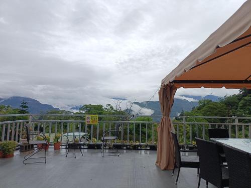 balcón con mesas y sillas y vistas a las montañas en 大方茶葉民宿, en Kung-t'ien-ts'un