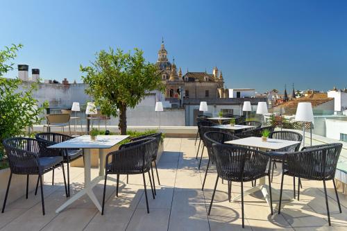 a patio with tables and chairs on a roof at H10 Casa de la Plata in Seville