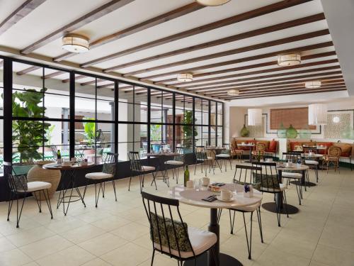 a dining room with tables and chairs and windows at H10 Casa de la Plata in Seville