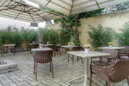 an outdoor patio with tables and chairs and umbrellas at Hotel Cosmos in Florence