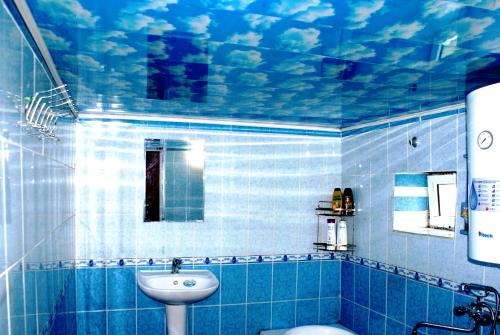 a blue tiled bathroom with a sink and a toilet at Spring Family Guest House in Tersak