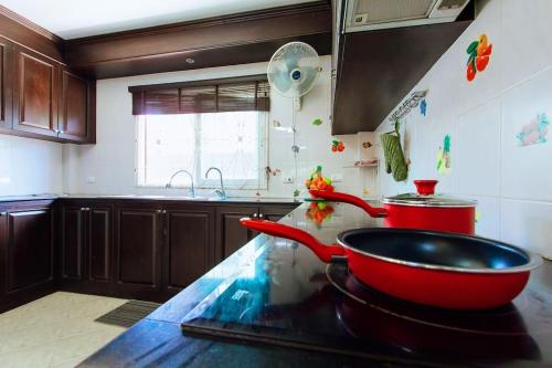 een keuken met een wastafel en een rode kom op een aanrecht bij PRIVATE RESIDENCE HOSTED by Sasithorn in Nong Prue